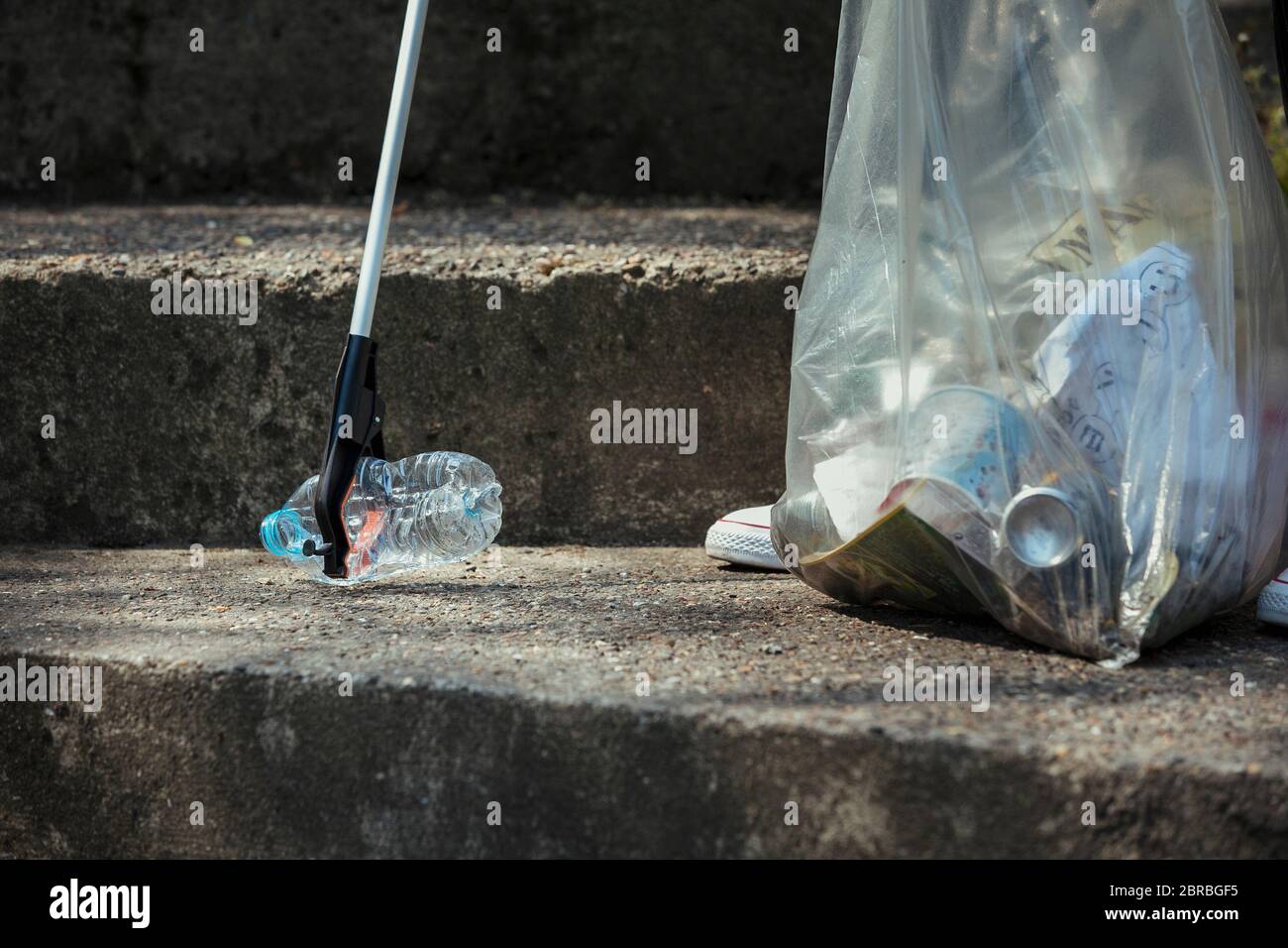 Un close-up di un irriconoscibile persona il prelievo di una bottiglia di plastica sulle strade. Foto Stock