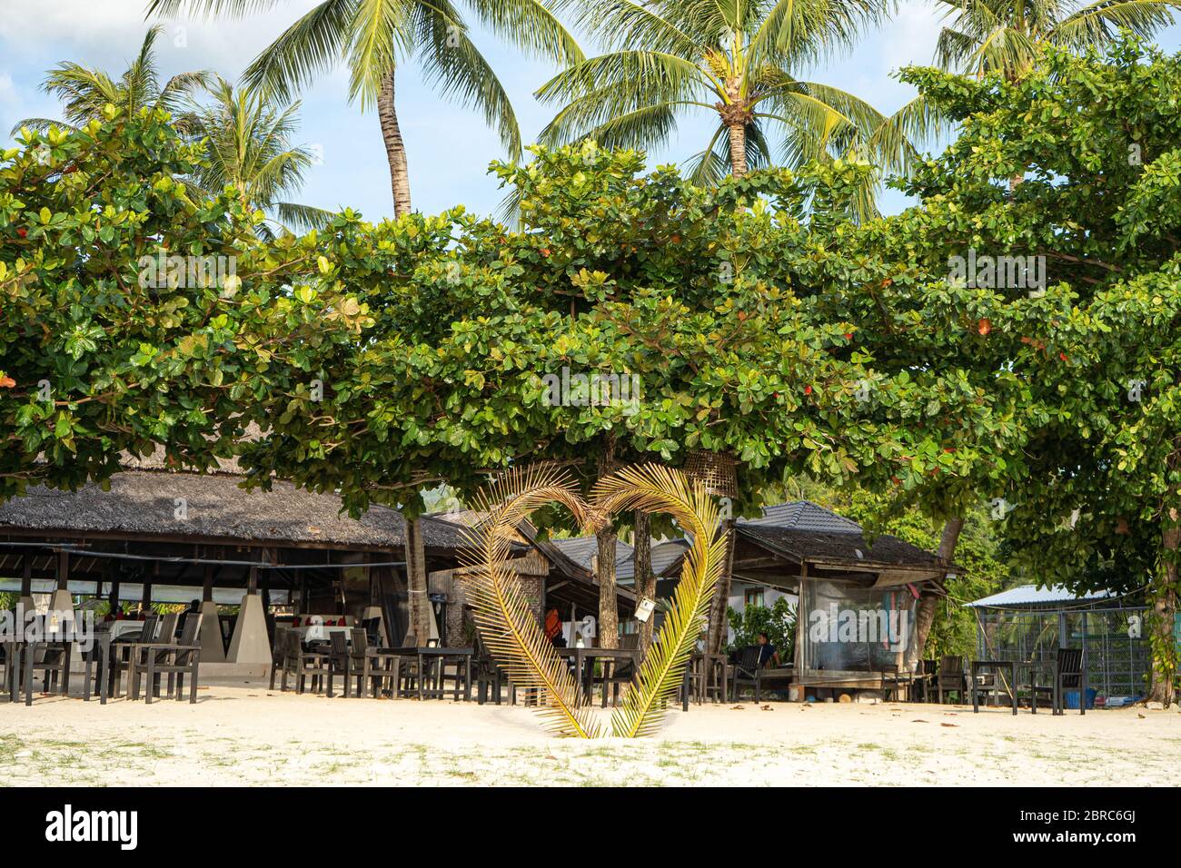 casa sulla spiaggia vicino a palme con vista sulla spiaggia di sabbia Foto Stock