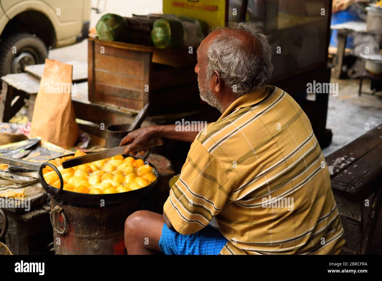 Un uomo che cucina il curry dell'uovo nel suo negozio di strada. Foto Stock