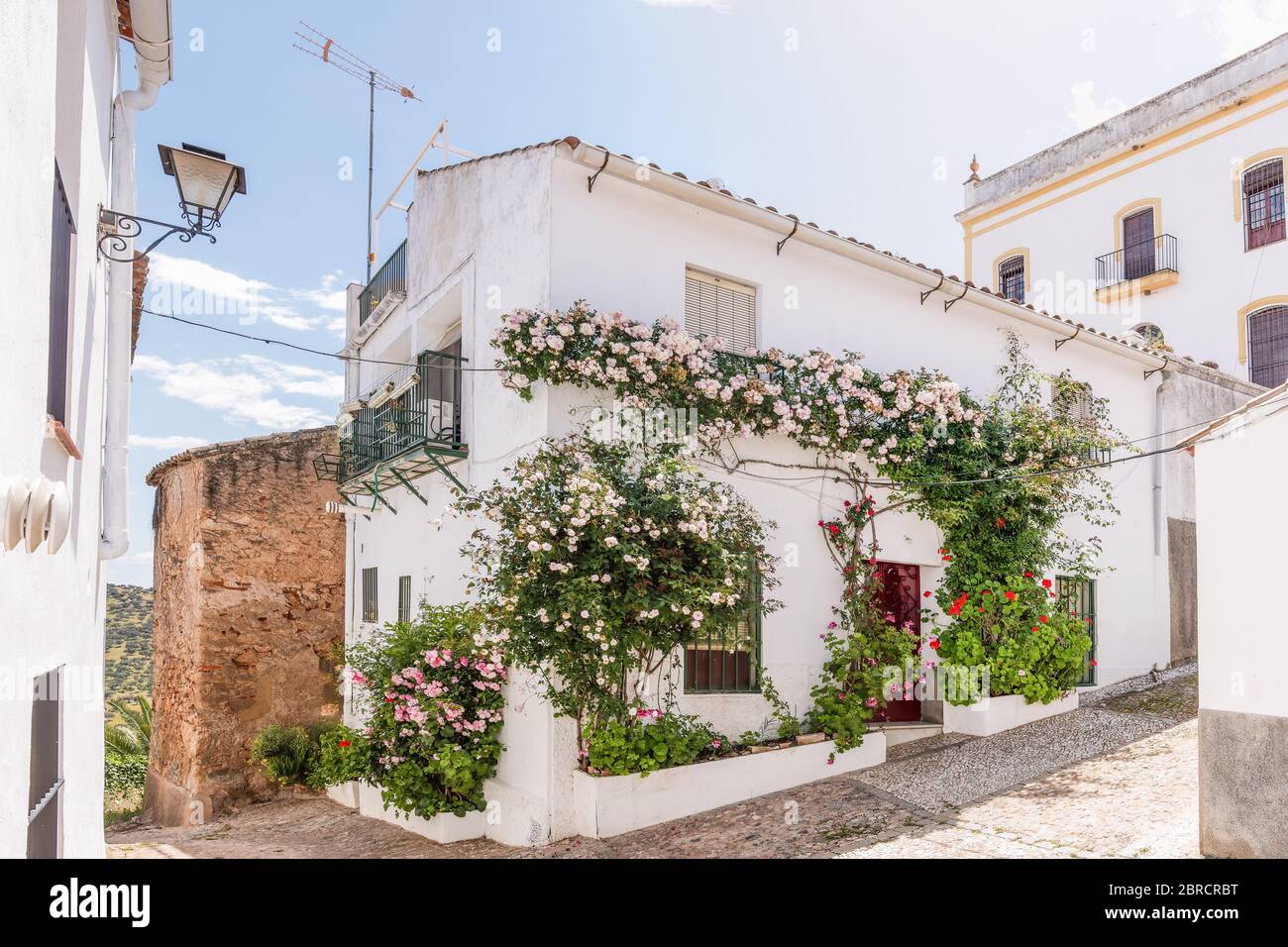 Vista di una bella casa bianca con fiori nella facciata nel villaggio di Zufre, Sierra de Aracena, Huelva, Spagna Foto Stock