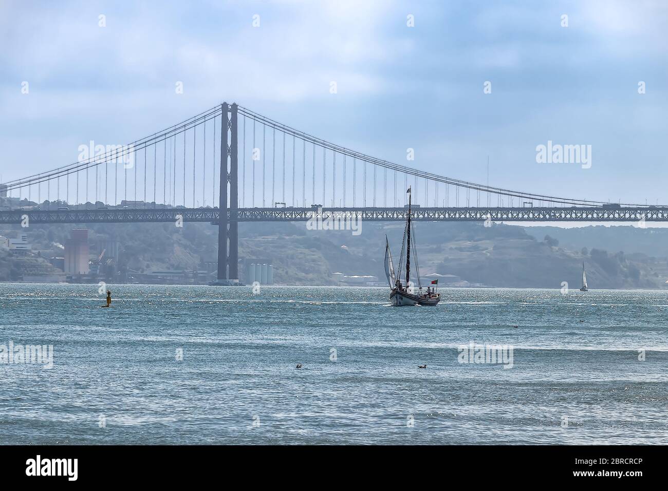 Barca a vela con ponte 25 aprile sullo sfondo con un po' di nebbia Foto Stock
