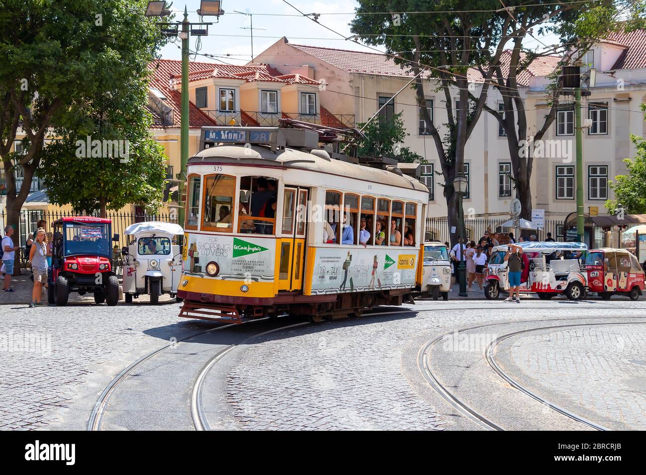Lisbona, Portogallo - 15 Luglio 2019: il famoso tram giallo 28 passando davanti al duomo di Santa Maria a Lisbona, Portogallo Foto Stock