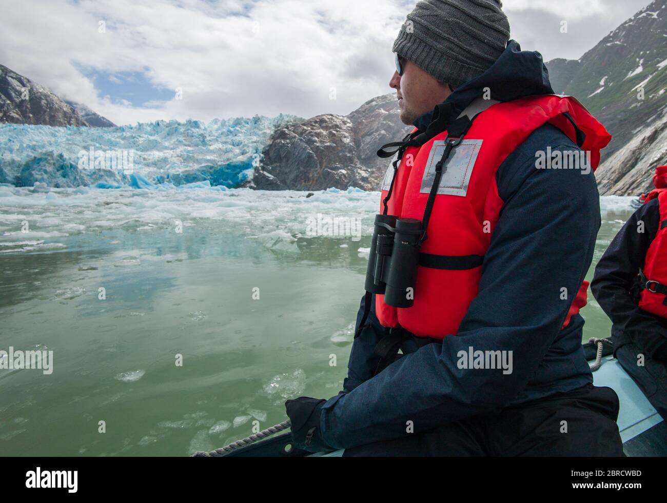 Il turista su una barca da sci da crociera avventura della piccola nave guarda gli iceberg calved dal ghiacciaio di South Sawyer, Tracy Arm Fjord, Alaska sudorientale, Stati Uniti. Foto Stock