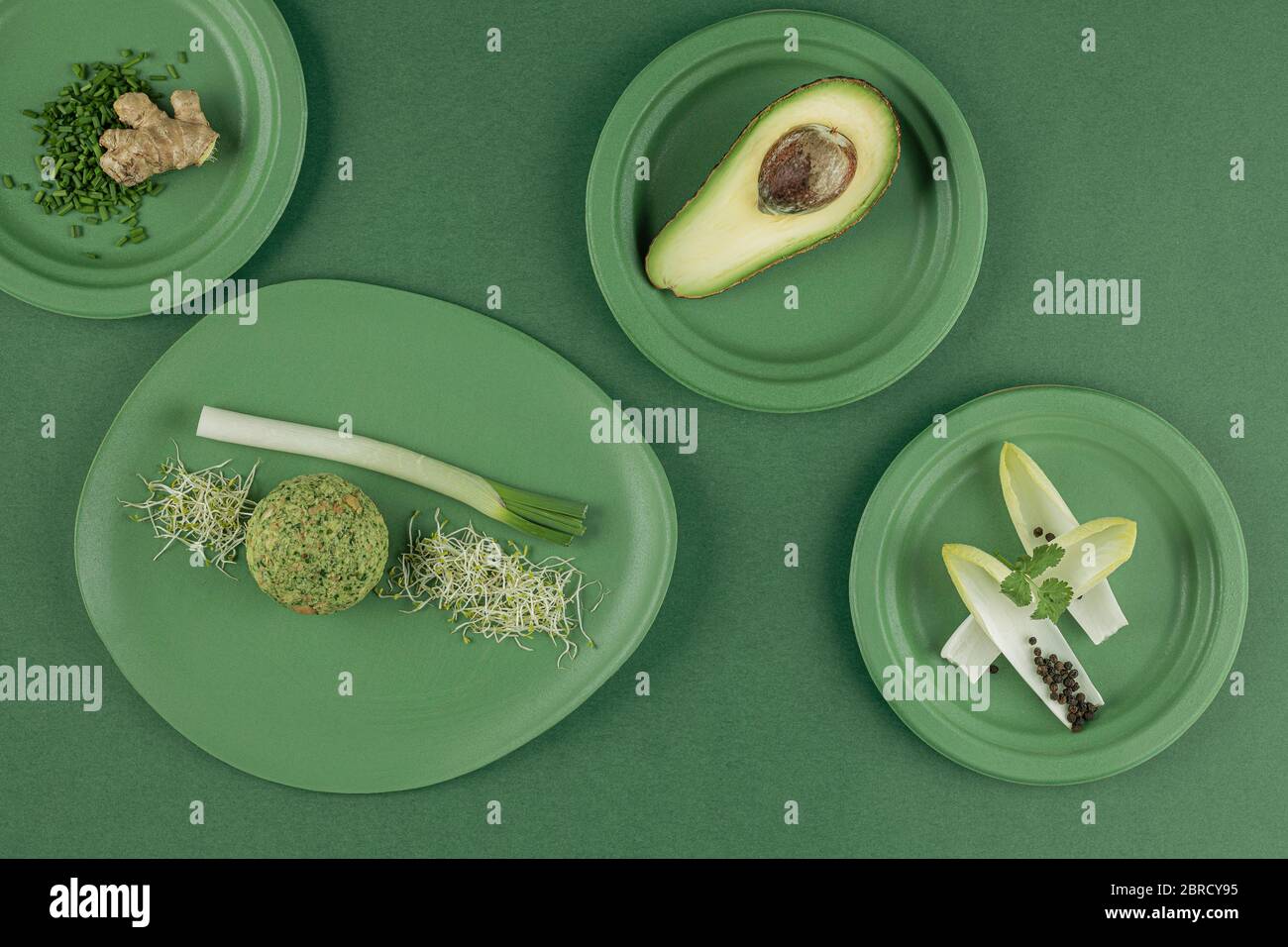 Tavolo in verde, piatto con gnocchi, gnocchi di spinaci, avocado, erba cipollina, crescione, porro, zenzero, vita morta, fotografia alimentare, fotografia in studio Foto Stock