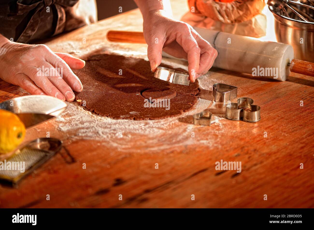 Mani da donna che pricking biscotti da pasta arrotolata, forma del cuore, mentre si cuoce, Germania Foto Stock