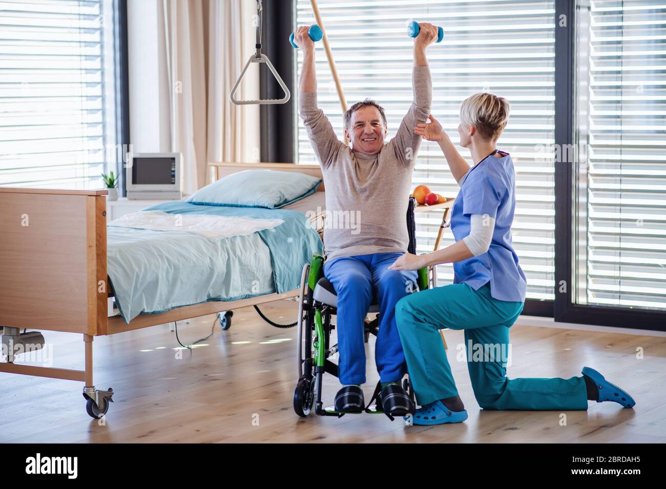 Un operatore sanitario e un paziente anziano in ospedale, fisioterapia. Foto Stock