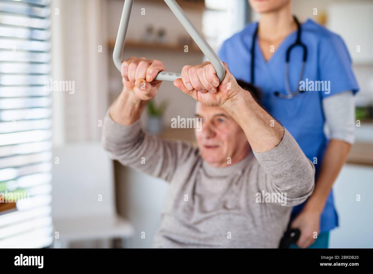 Un operatore sanitario e un paziente anziano in ospedale, fisioterapia. Foto Stock
