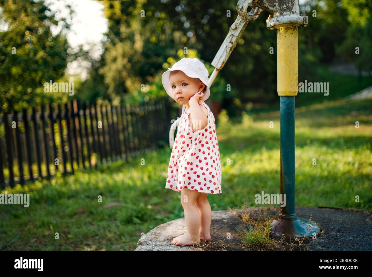 Una bambina che si trova all'aperto in giardino in estate. Foto Stock