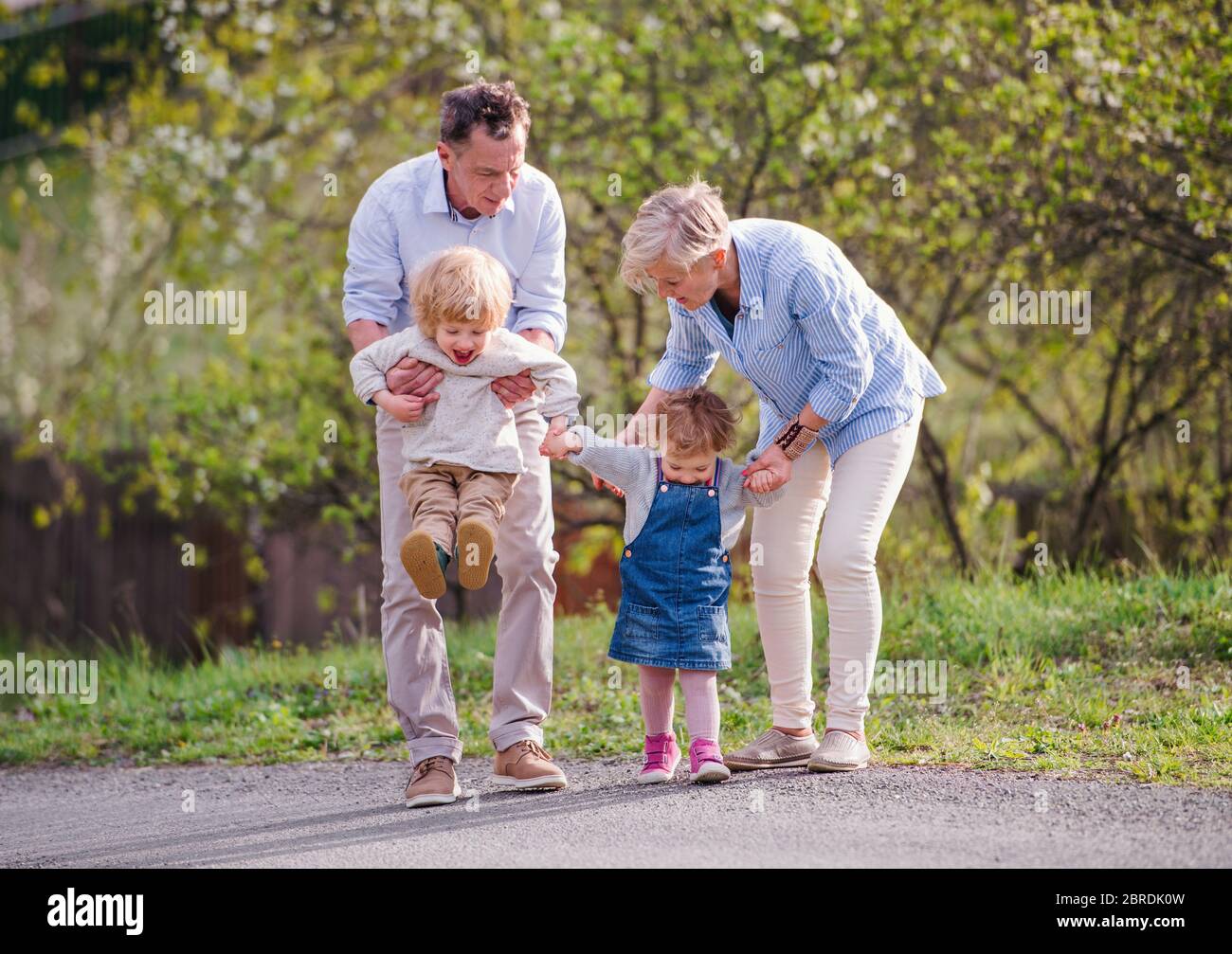 Nonni anziani con nipoti che camminano in natura in primavera. Foto Stock