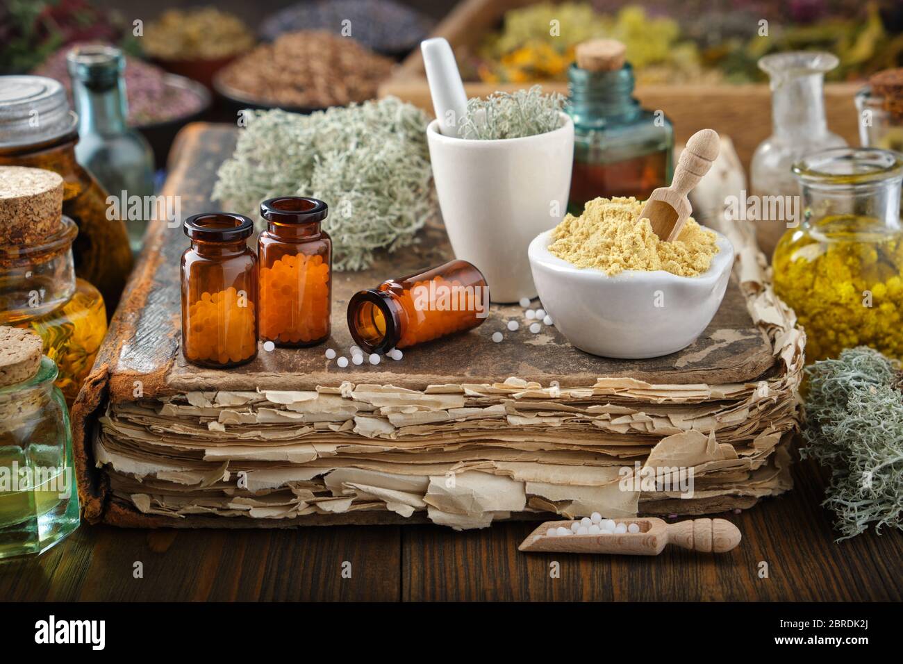 Bottiglie di farmaci omeopatici, mortai di sostanze minerali e piante medicinali. Flaconi per infusione ed erbe curative sullo sfondo. Omeopatia medica Foto Stock