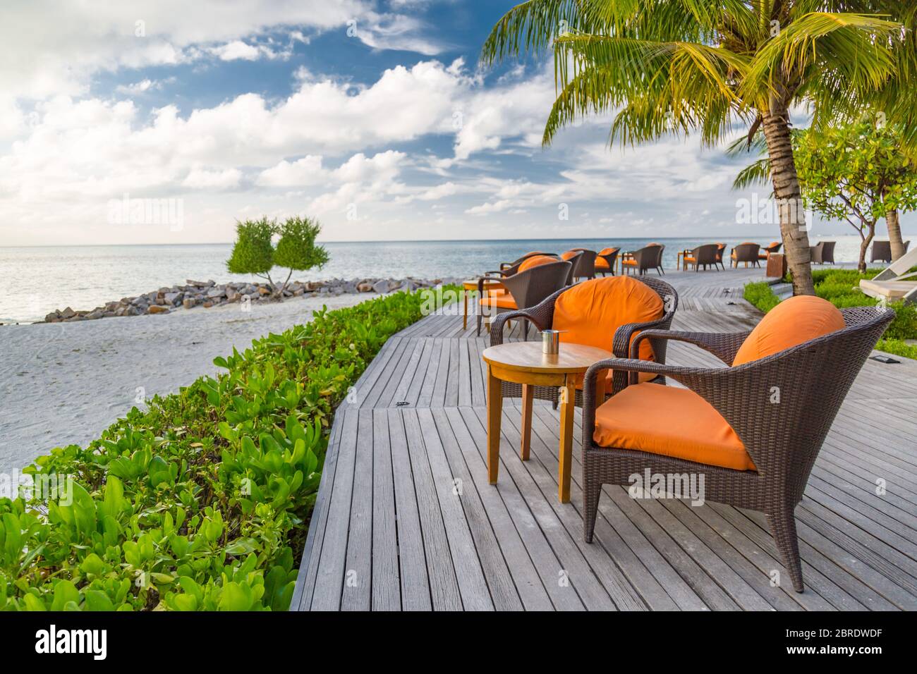 Tavolo al ristorante sulla spiaggia. Elegante bar esterno sul mare con sedie e tavoli su terrazza in legno Foto Stock