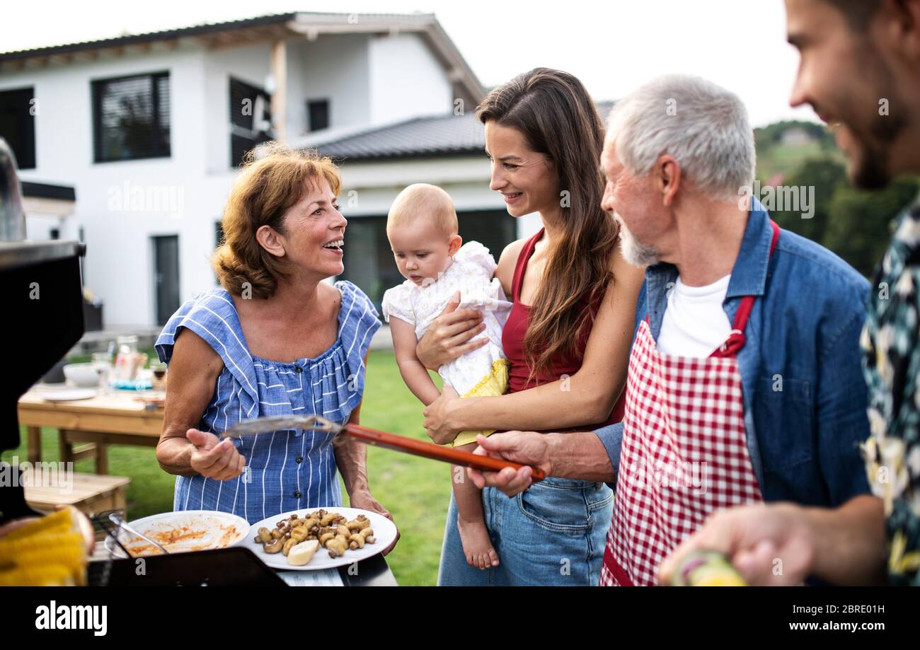 Ritratto di famiglia multigeneration all'aperto su barbecue giardino, grigliatura. Foto Stock