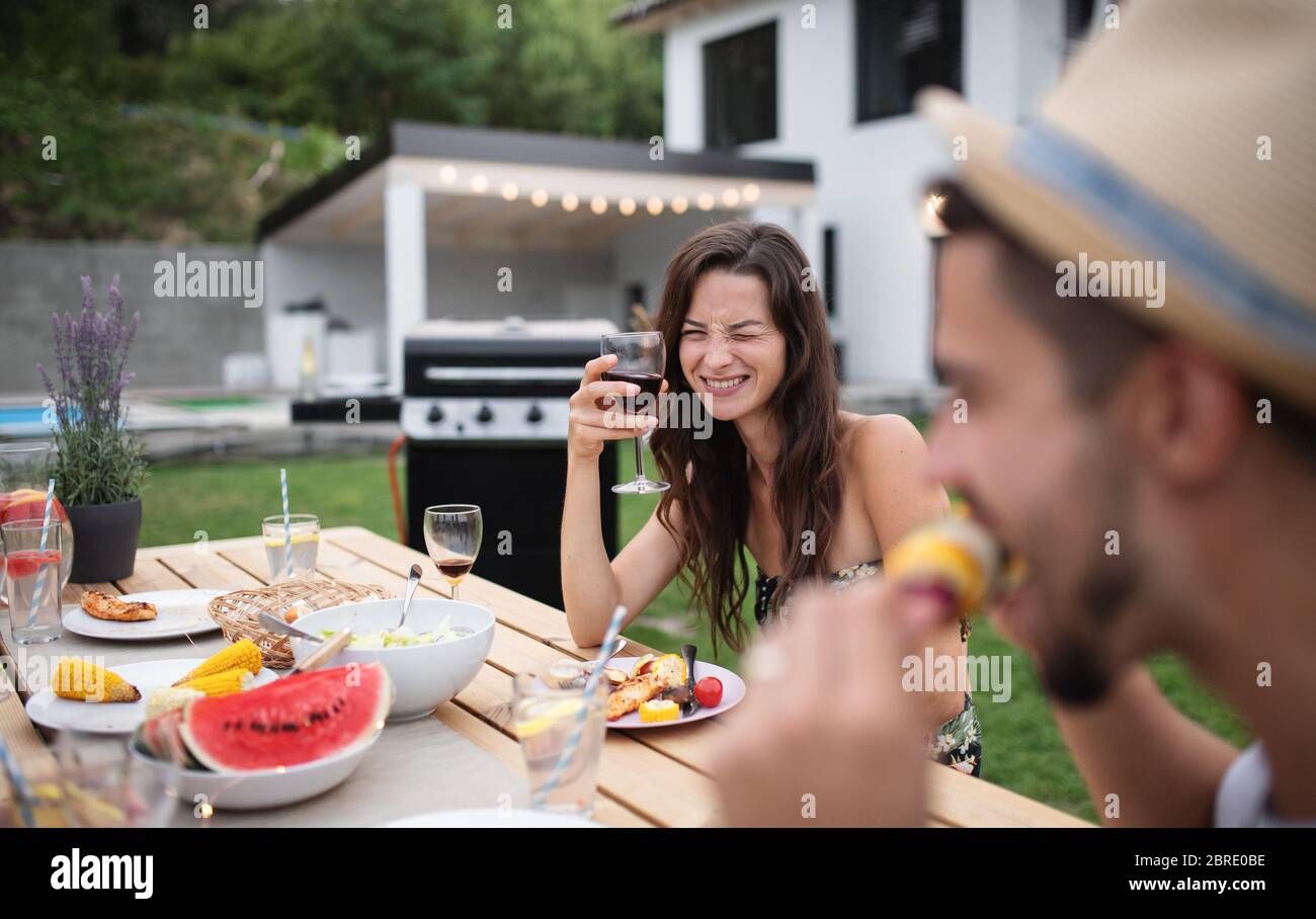 Ritratto di famiglia con vino seduto a tavola all'aperto su barbecue giardino. Foto Stock