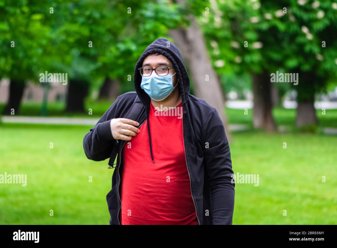 Uomo che indossa la maschera che cammina da solo nel parco Foto Stock