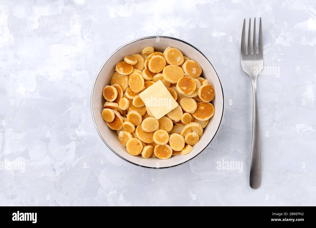 Minuscoli cereali con pancake. Colazione fatta in casa con burro su sfondo grigio Foto Stock