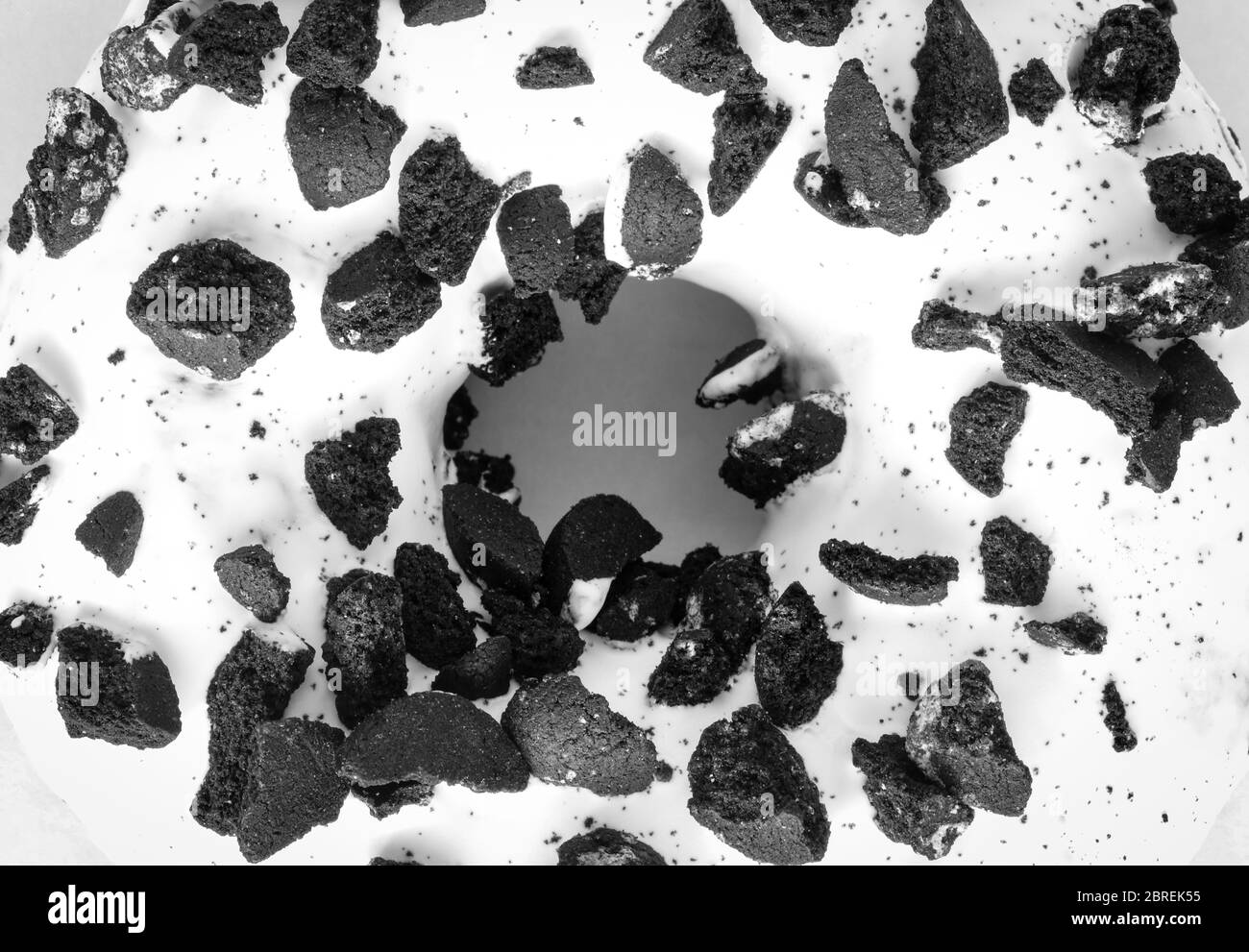 Immagine piatta della ciambella ad anello con smalto bianco cosparsa di biscotti neri Foto Stock