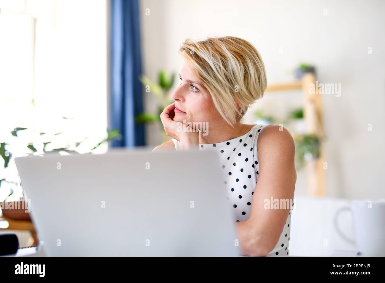 Triste giovane donna d'affari con il laptop in casa in ufficio, lavorando. Foto Stock
