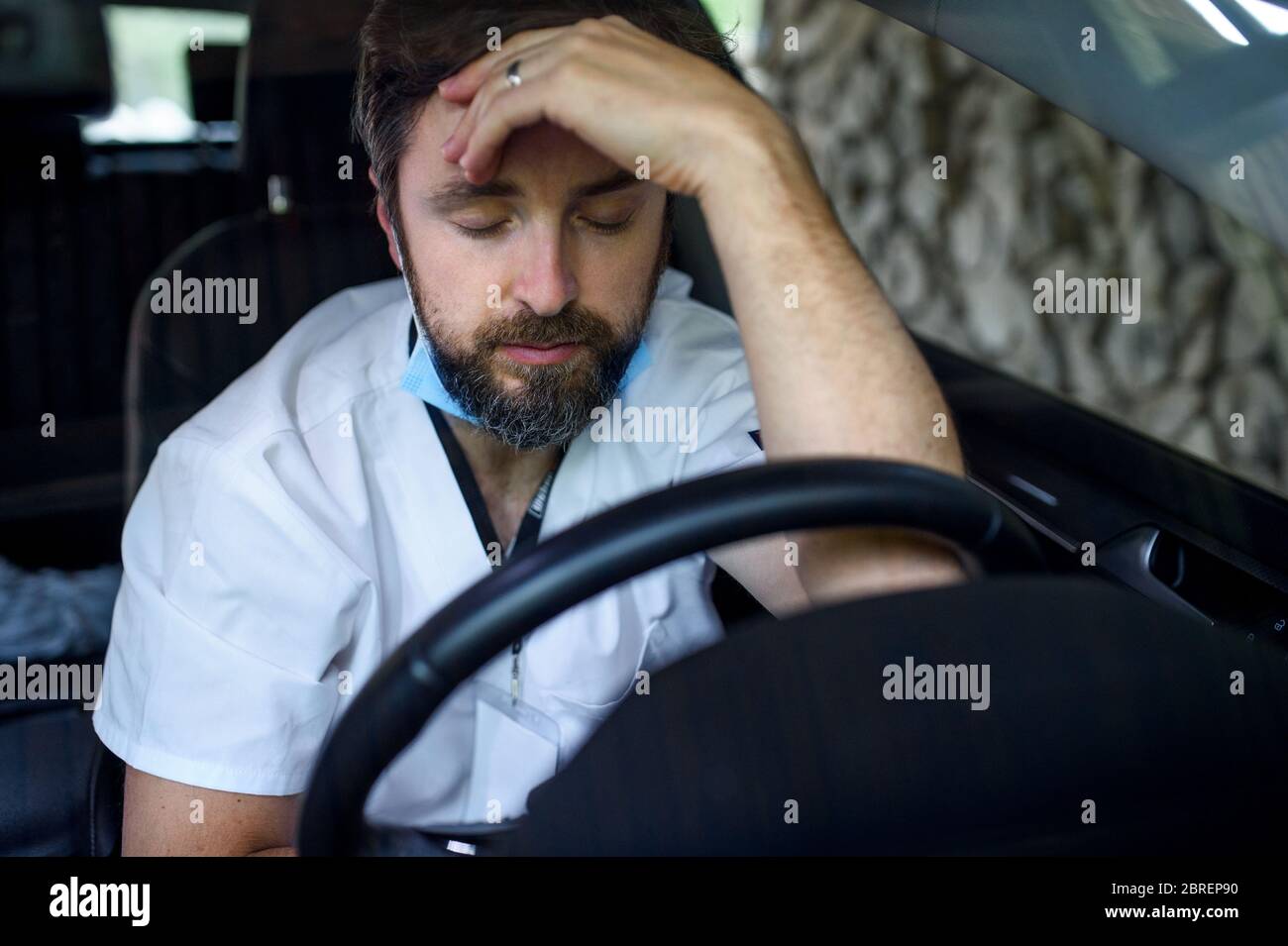 Stanco e esausto medico seduto in macchina dopo un lungo e difficile turno. Foto Stock
