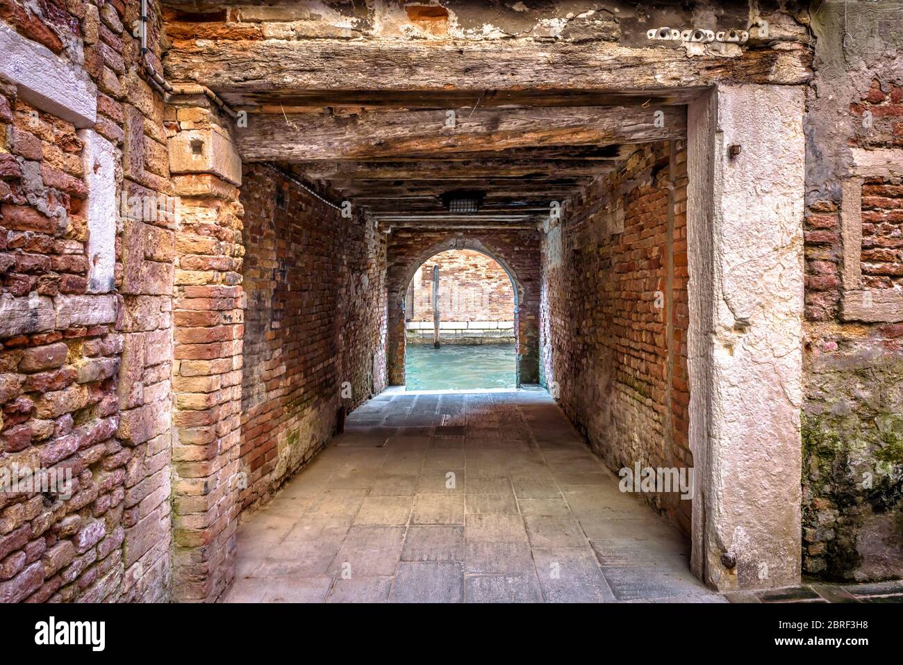 Uscita per il canale d'acqua dal cortile, Venezia, Italia. Corridoio vintage del cortile dell'area residenziale. Antica architettura di Venezia. Vecchia strada del Foto Stock