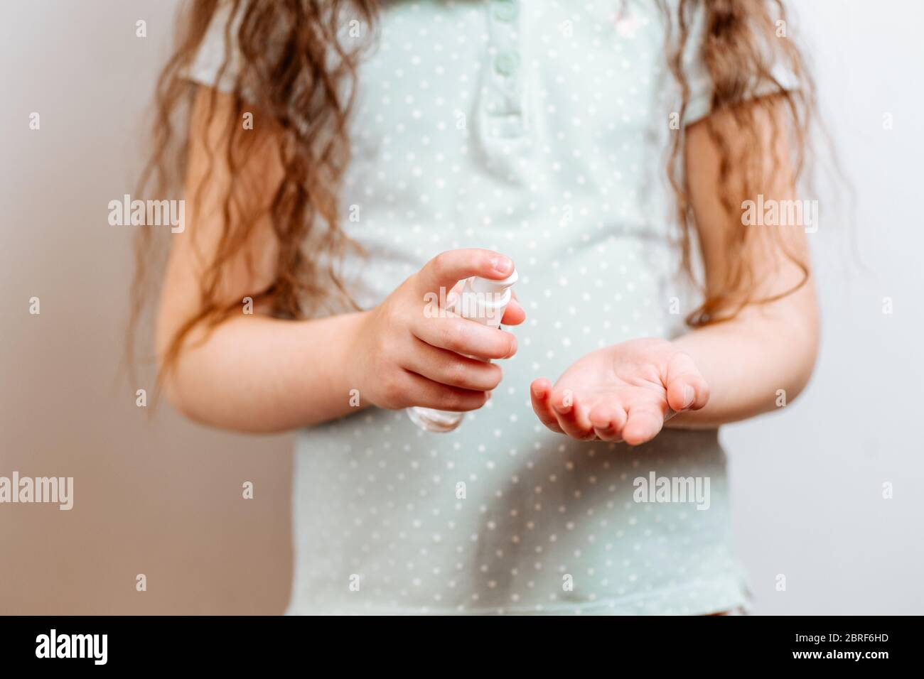 Il bambino usa un gel antisettico antibatterico per disinfettare le mani dai batteri. Concetto di igiene e di sanità Foto Stock