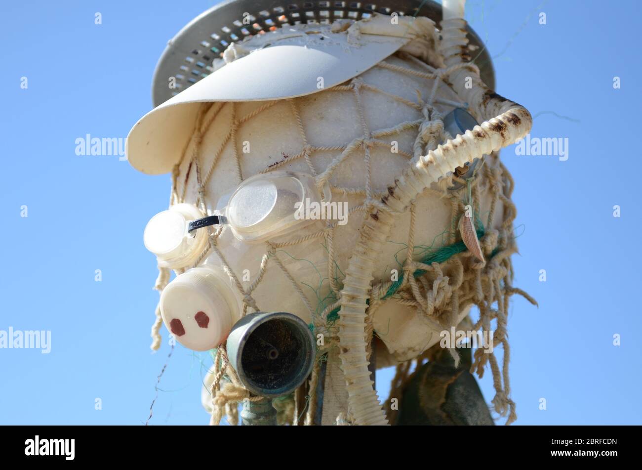 Primo piano Scarecrow fatto di plastica e altri rifiuti gettati fuori dal mare. Plastica, reti, filo spinato, lavelli. Vicino al mare sulla spiaggia Foto Stock