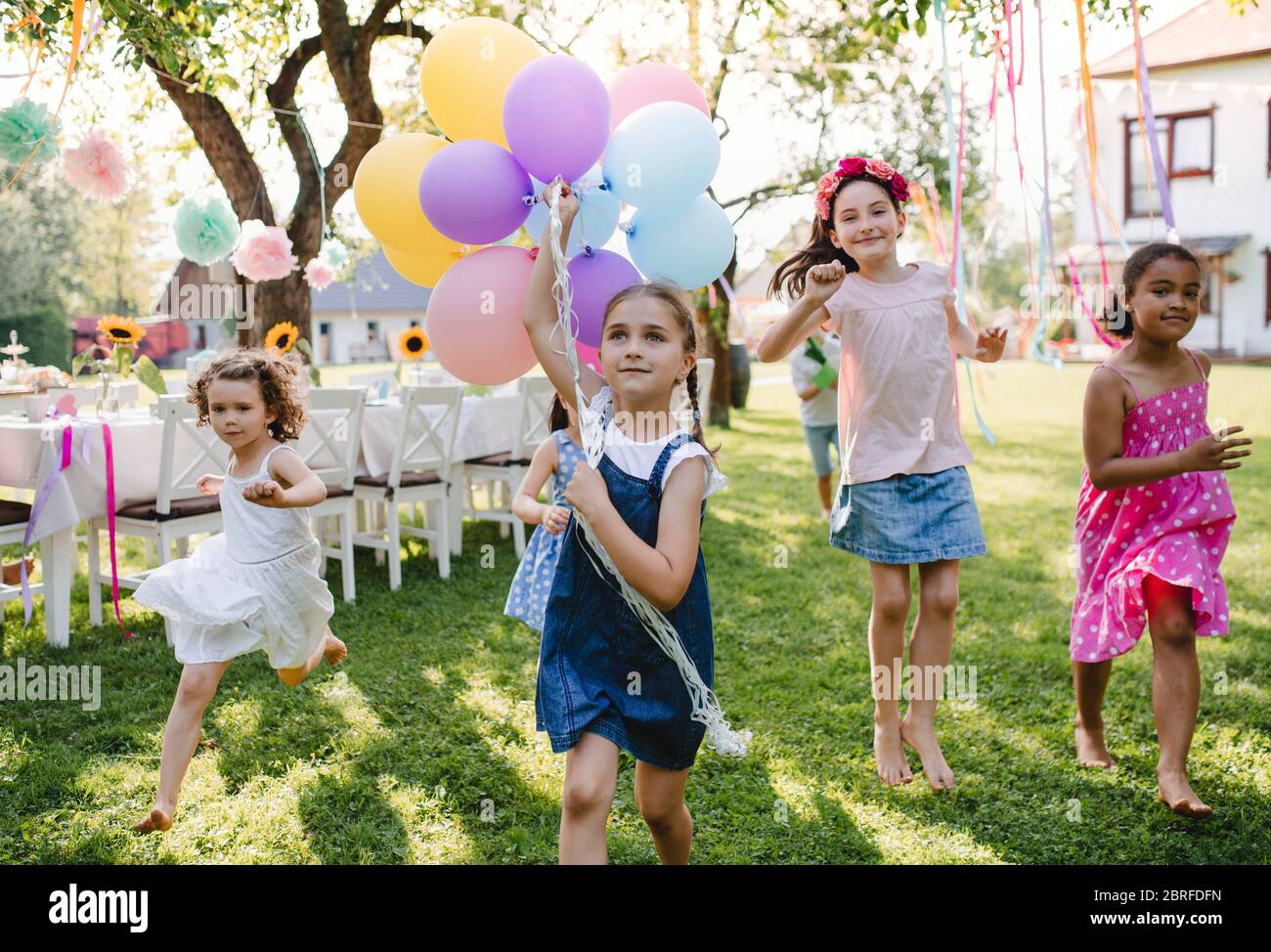 Bambini piccoli all'aperto in giardino in estate, giocando con palloncini. Foto Stock