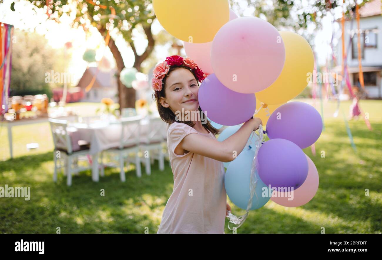Piccola ragazza all'aperto in giardino in estate, giocando con palloncini. Foto Stock