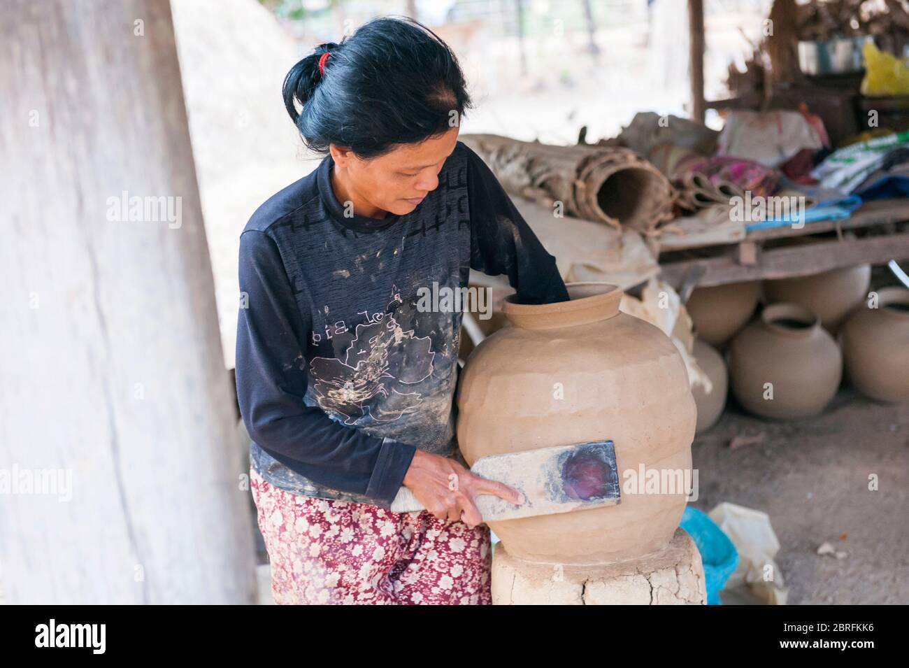 Una donna che forma una pentola di argilla usando un pipistrello di legno. Provincia di Kampong Chhnang, Cambogia, Sud-est asiatico Foto Stock