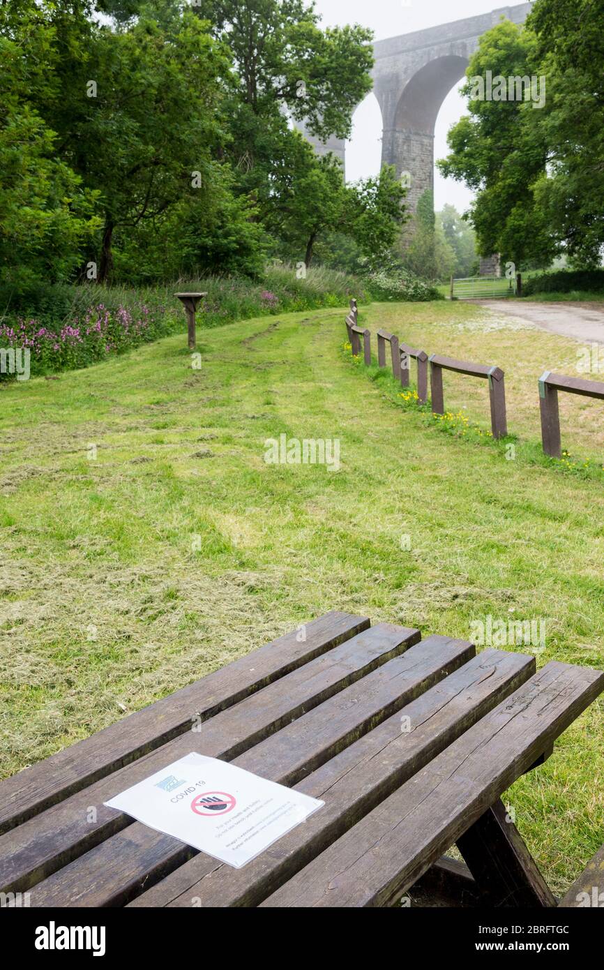 Avviso del Consiglio pinzato su un tavolo da picnic in un parco di campagna vuoto che vieta l'uso del tavolo a causa delle norme di salute e sicurezza del Covid 19. Foto Stock