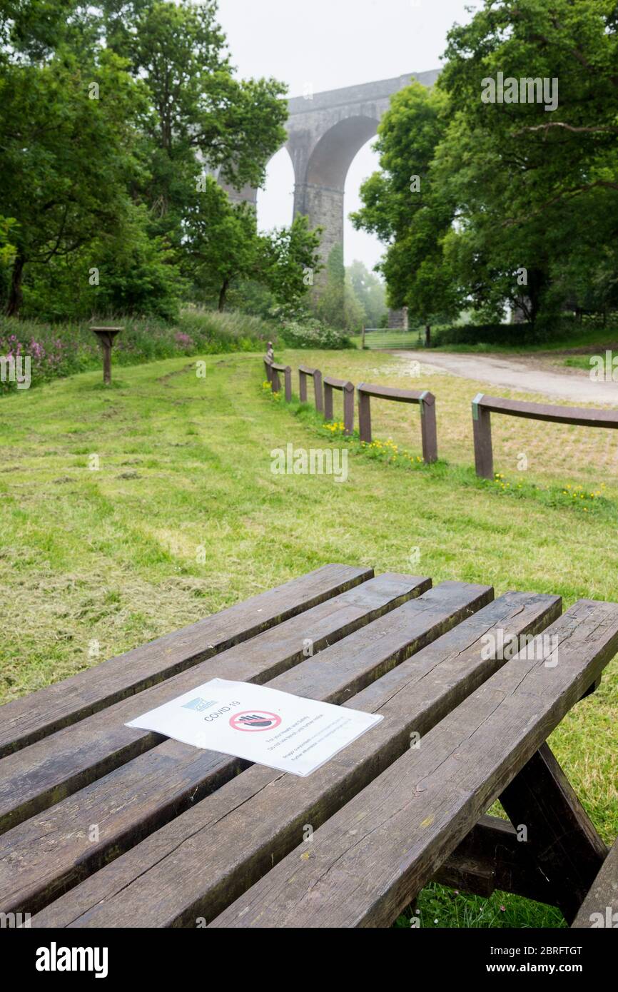 Avviso del Consiglio pinzato su un tavolo da picnic in un parco di campagna vuoto che vieta l'uso del tavolo a causa delle norme di salute e sicurezza del Covid 19. Foto Stock