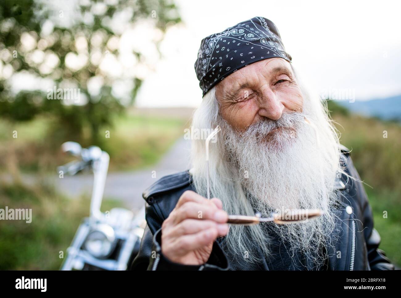 Uomo anziano con moto in campagna, winking. Foto Stock