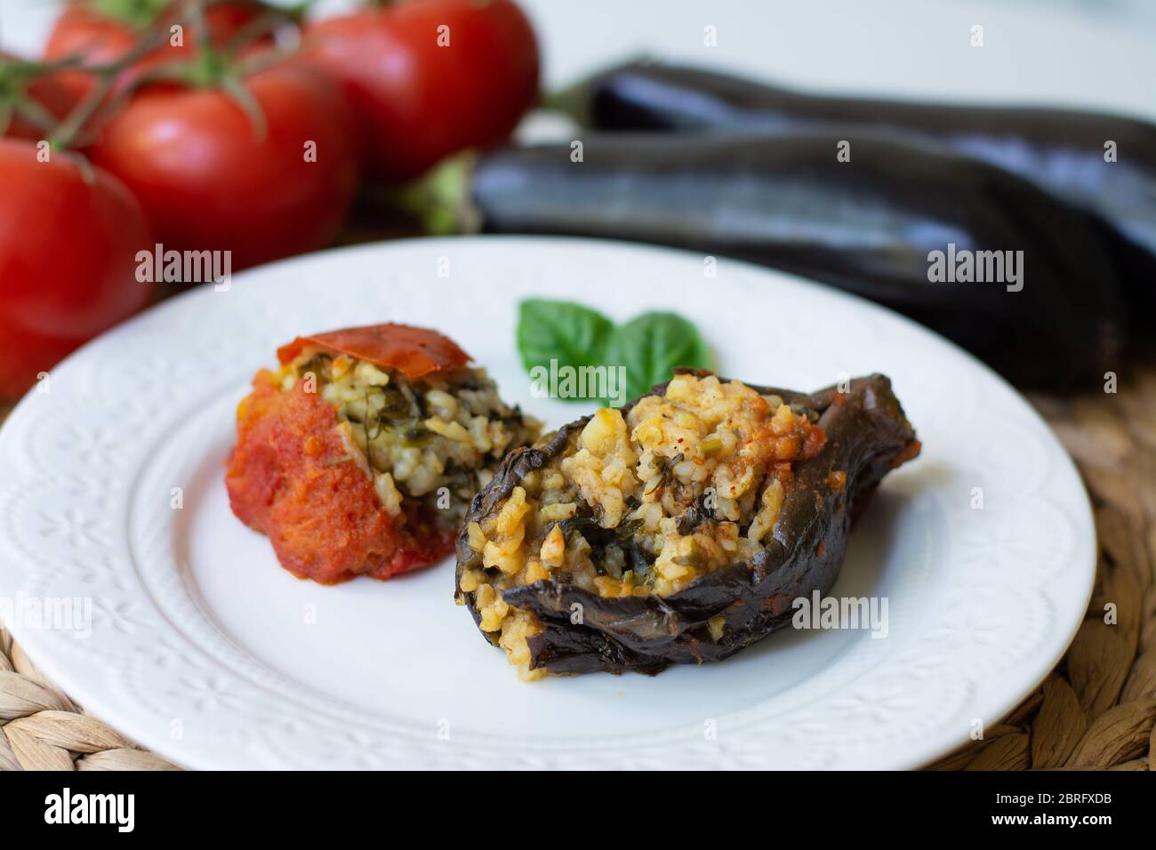 Il tradizionale dolma azerbaigiano delle melanzane ha anche chiamato tre sorelle fatte vegane: Un'melanzana e un pomodoro farcito con riso piccante e basilico Foto Stock