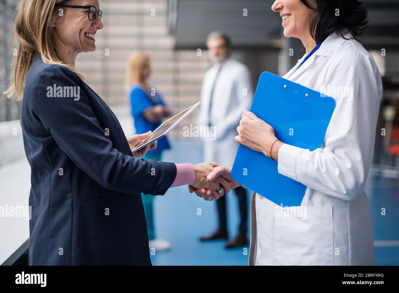 Medico che parla con il rappresentante di vendita farmaceutico, scuotendo le mani. Foto Stock