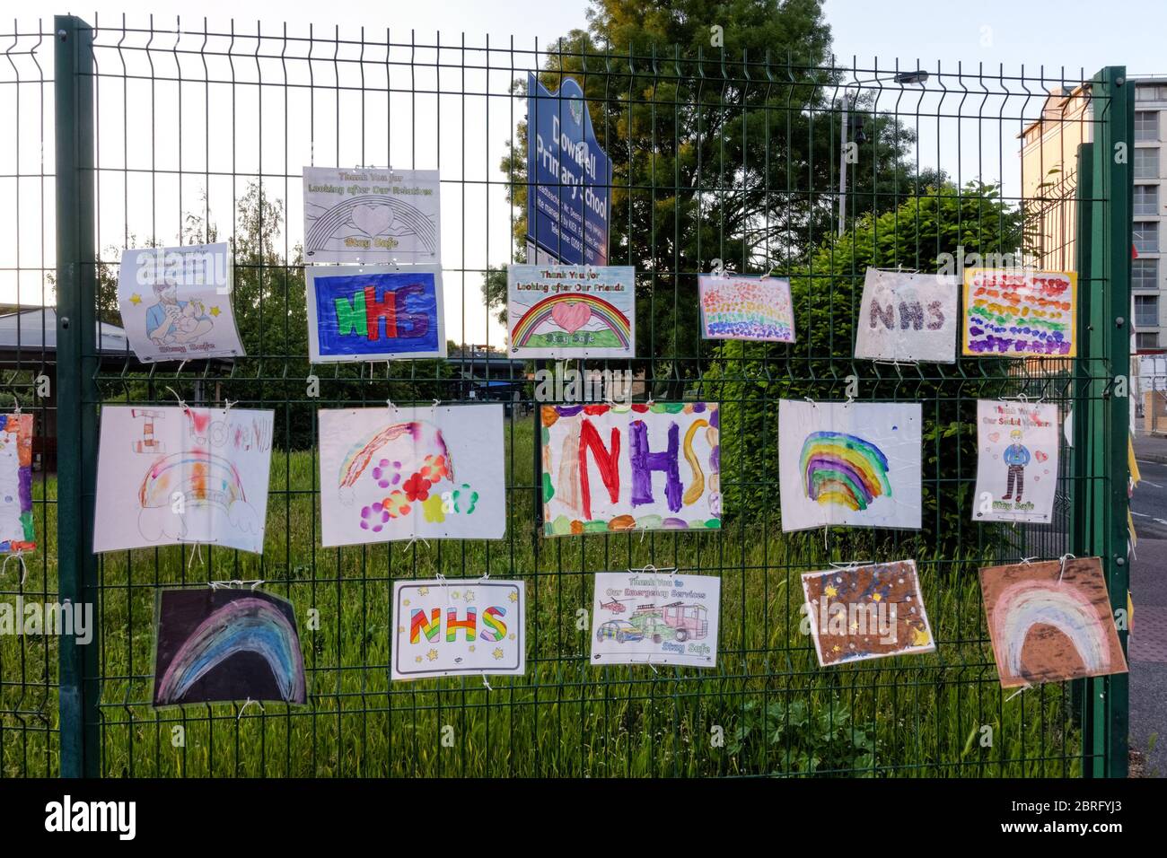 Disegni arcobaleno, che supportano NHS, presso le ringhiere della scuola primaria temporaneamente chiuso a causa del blocco del coronavirus, Londra, Inghilterra Regno Unito Regno Unito Foto Stock