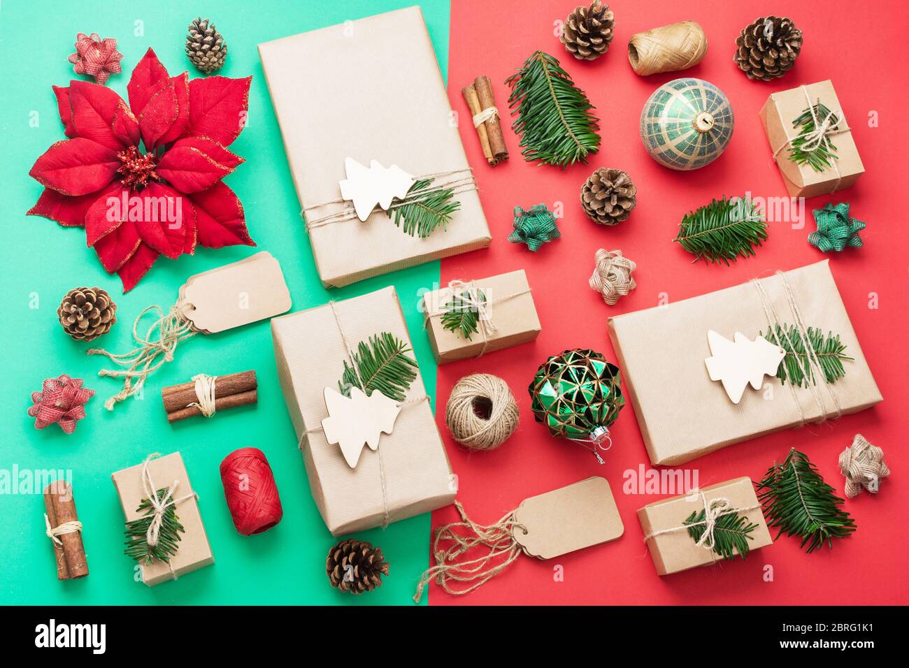 Composizione di Natale senza scarti in rosso verde marrone. Vista dall'alto di presenta avvolti in carta marrone artigianale, pineconi, bastoncini di cannella, spago di iuta e ornamenti di woden, baubles, fuoco selettivo Foto Stock