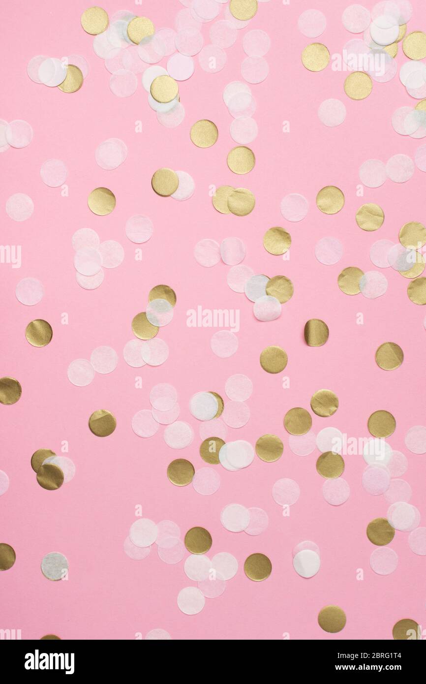 Coriandoli di carta in rosa chiaro, bianco e oro pastello su sfondo rosa, vista dall'alto, selettivo Foto Stock