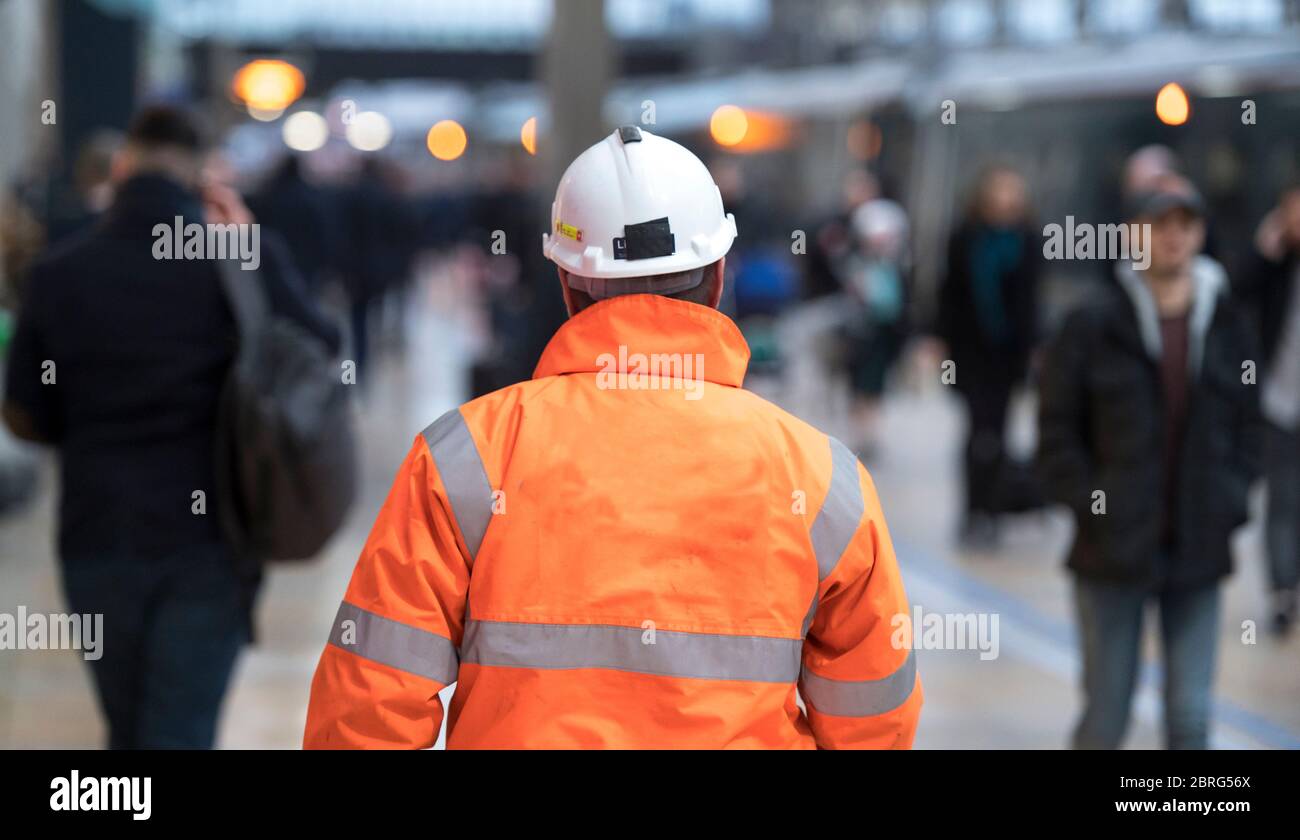 Operaio di manutenzione che cammina attraverso una stazione ferroviaria in Inghilterra, Regno Unito. Foto Stock