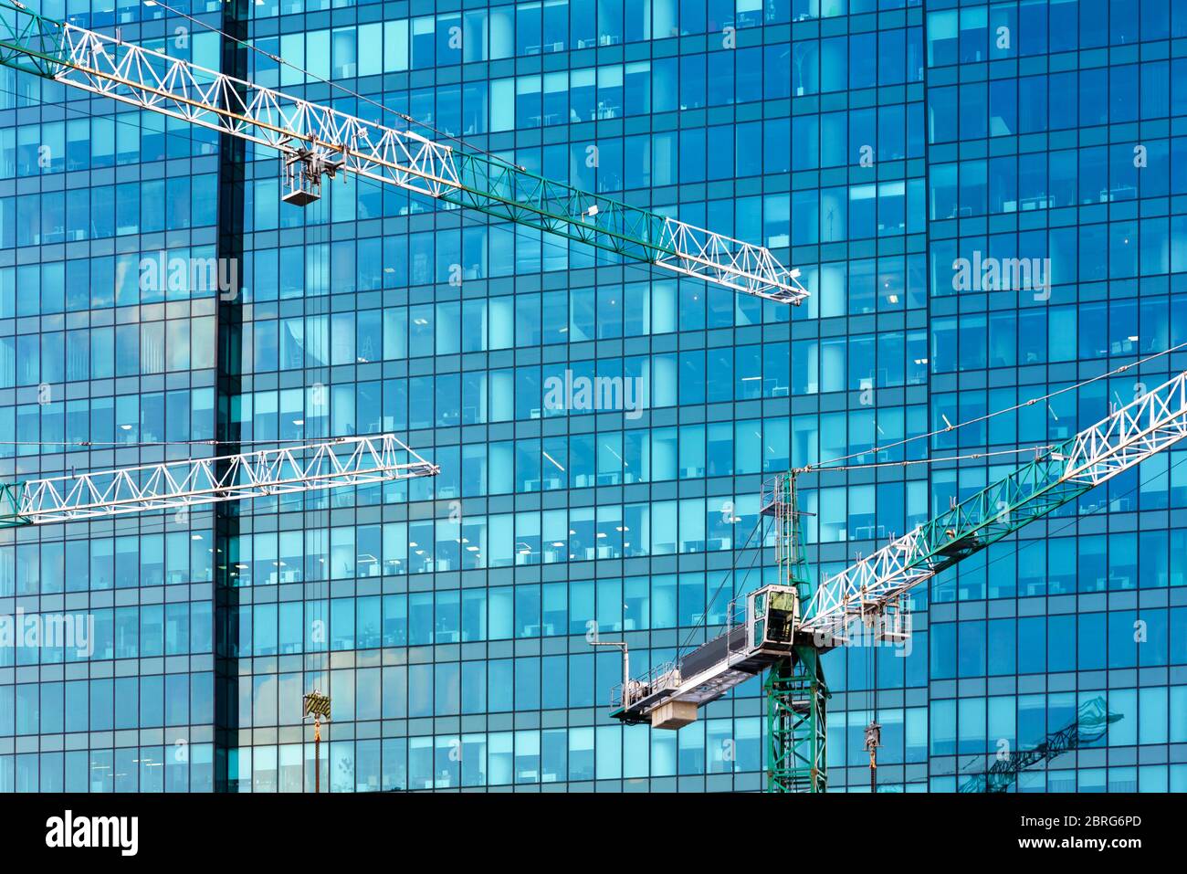 Gru di costruzione sullo sfondo di un edificio moderno. Facciata in vetro di grattacieli nel cantiere. Foto Stock