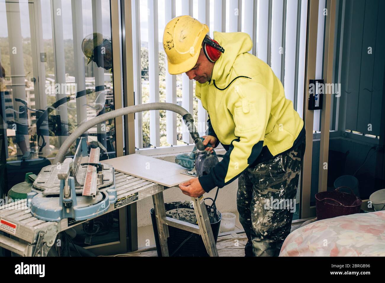 Il costruttore professionale spalma la colla cementizia sulla piastrella in ceramica con una cazzuola. Riparazione, revisione, tiler a contratto. Foto Stock