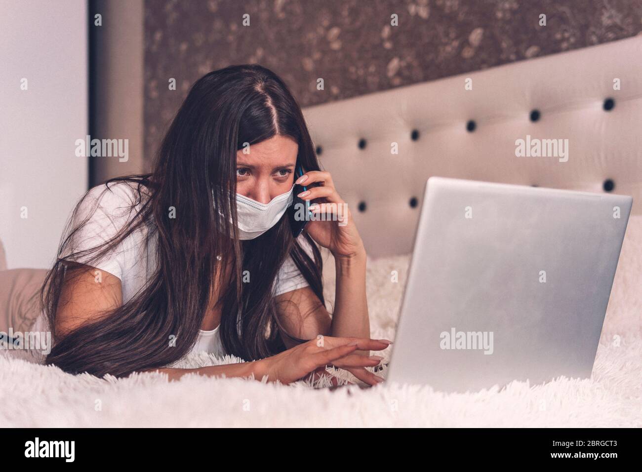 Donna malata che lavora su un computer portatile sdraiato a letto, influenza da febbre alta, riposo. Lavoro da casa, Covid-19. Lavoro a distanza. Lavoro a distanza Foto Stock