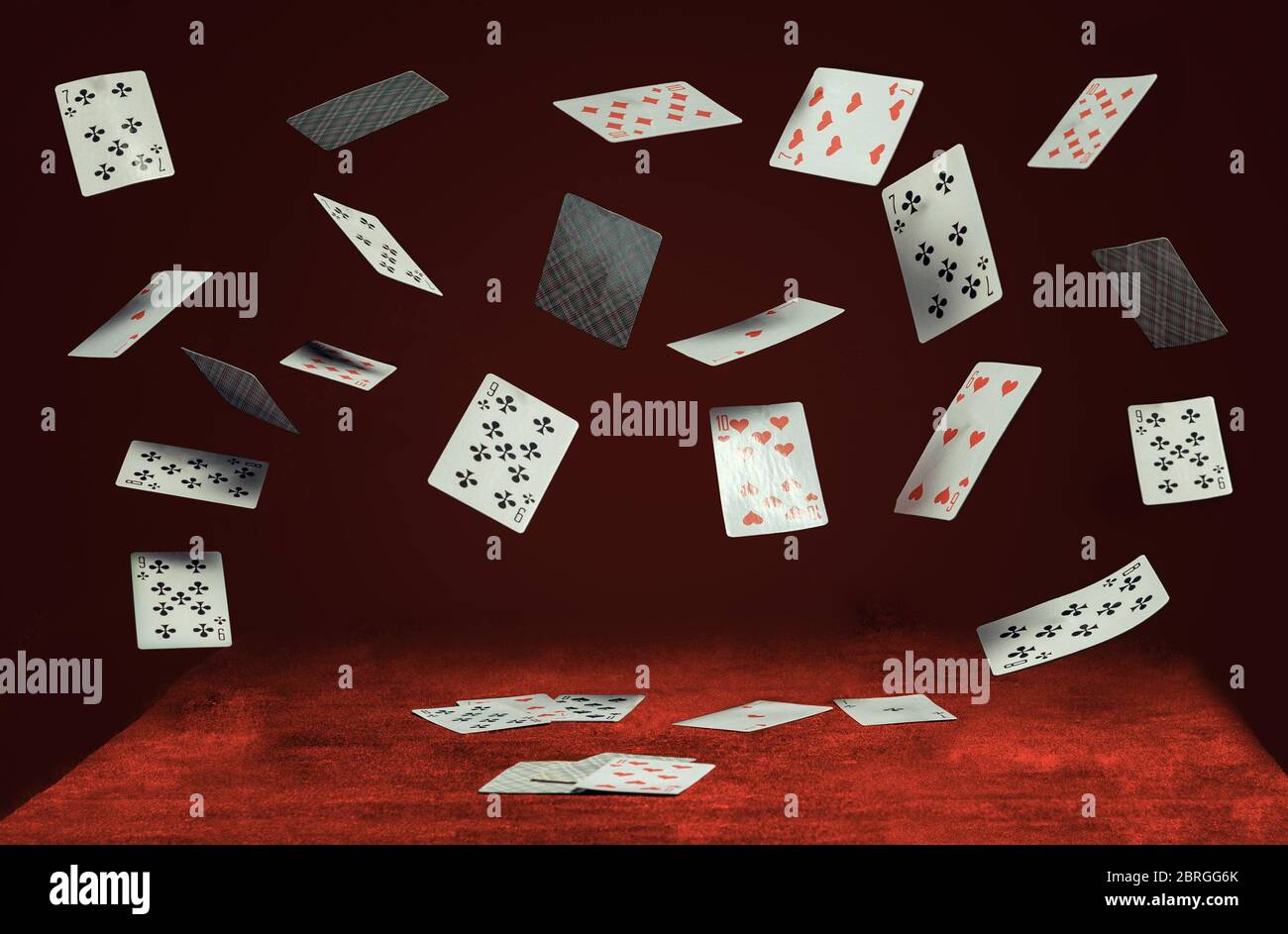 le carte da gioco cadono su un tavolo con un panno rosso Foto Stock