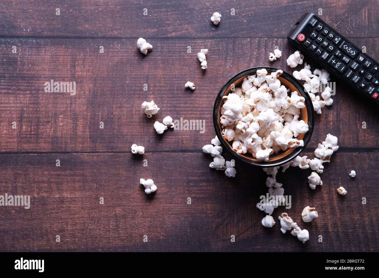 Vista dall'alto della ciotola di popcorn e del telecomando TV sul tavolo Foto Stock