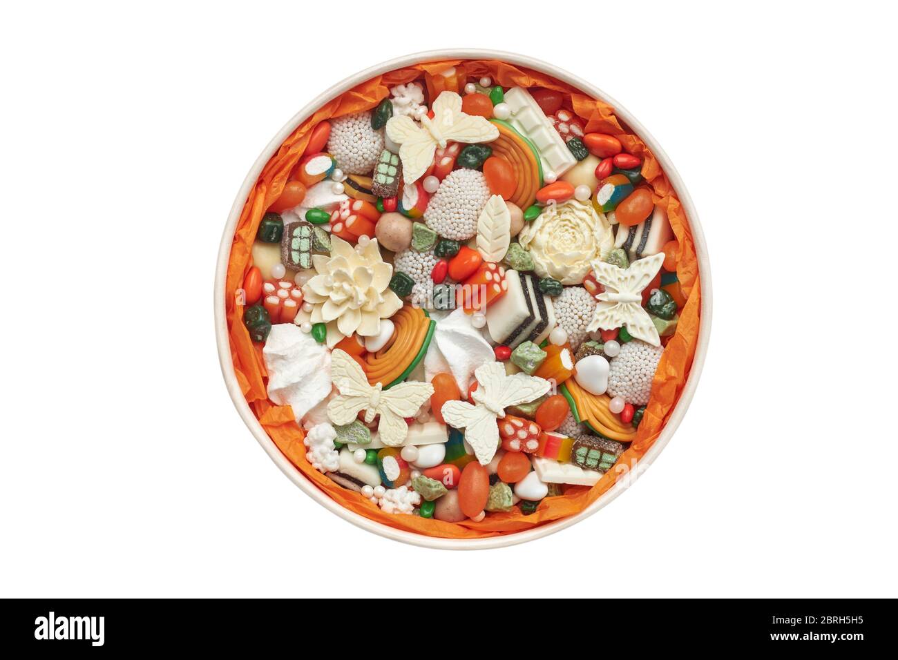 Scatola rotonda riempita con caramelle arancioni e cioccolato artigianale isolato su sfondo bianco. Foto Stock