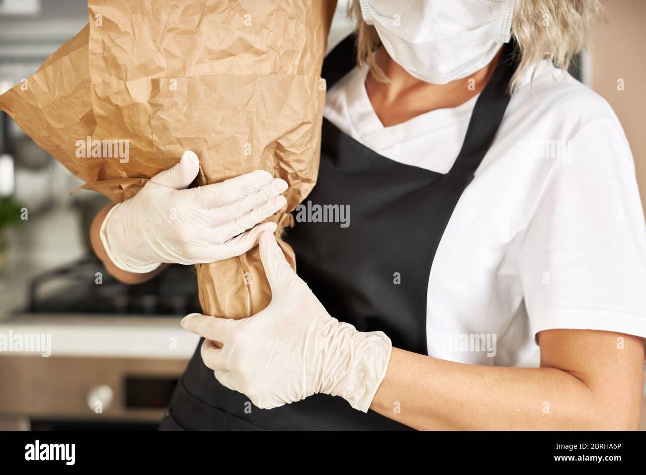 La giovane donna tiene un bouquet grande imballato in carta artigianale nelle sue mani. Foto Stock