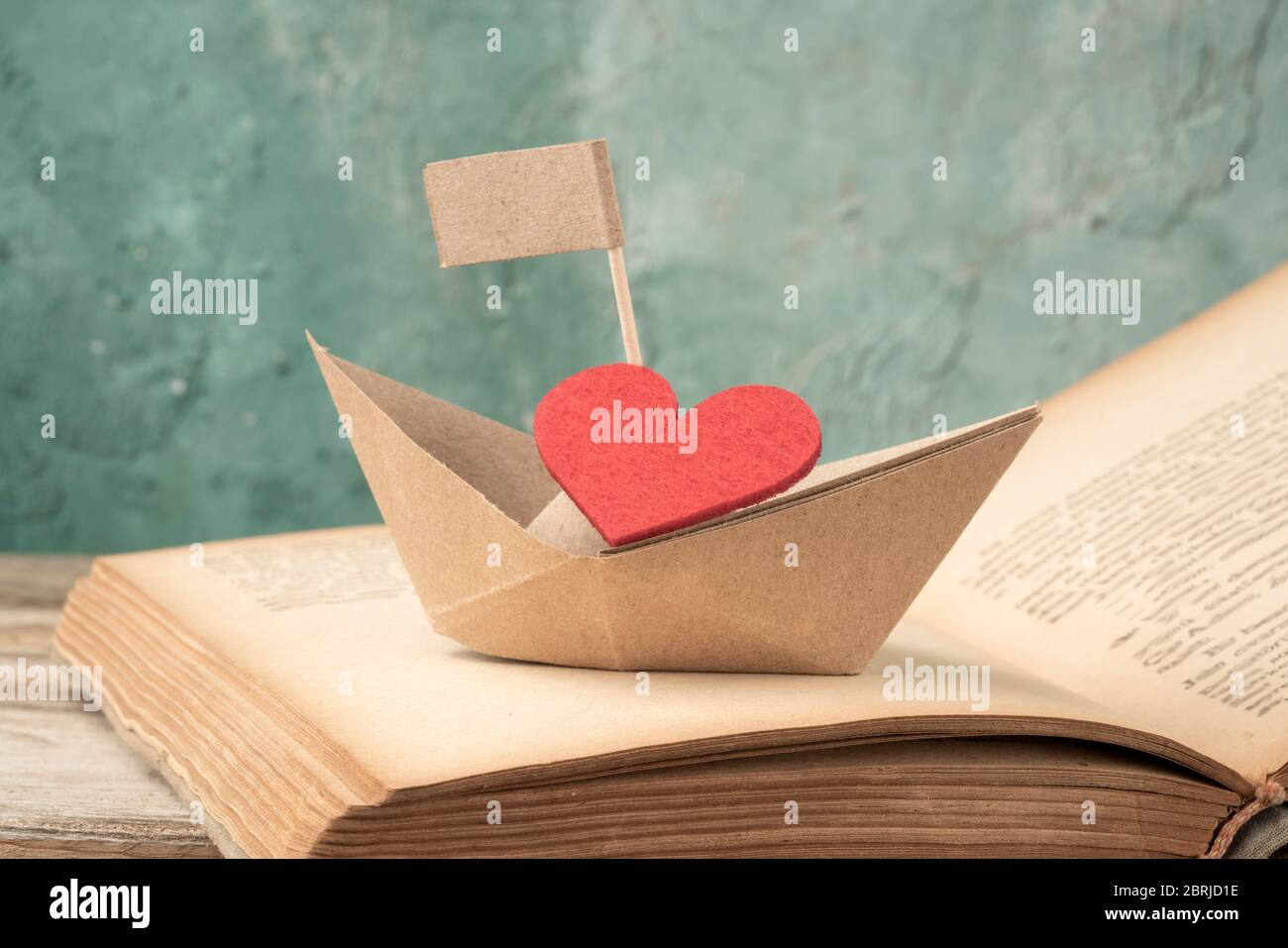 carta barca su un vecchio libro a tavola. Barca a vela di carta origami  artigianale su un libro aperto Foto stock - Alamy