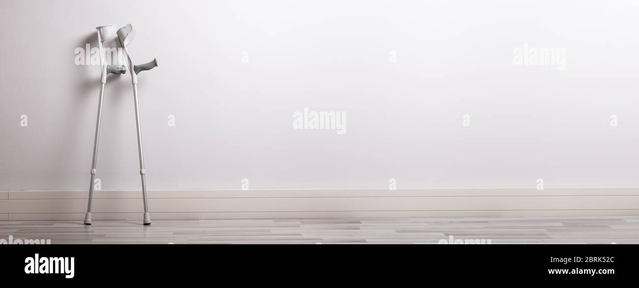 Due stampelle appoggiate a parete in Clinica Foto Stock