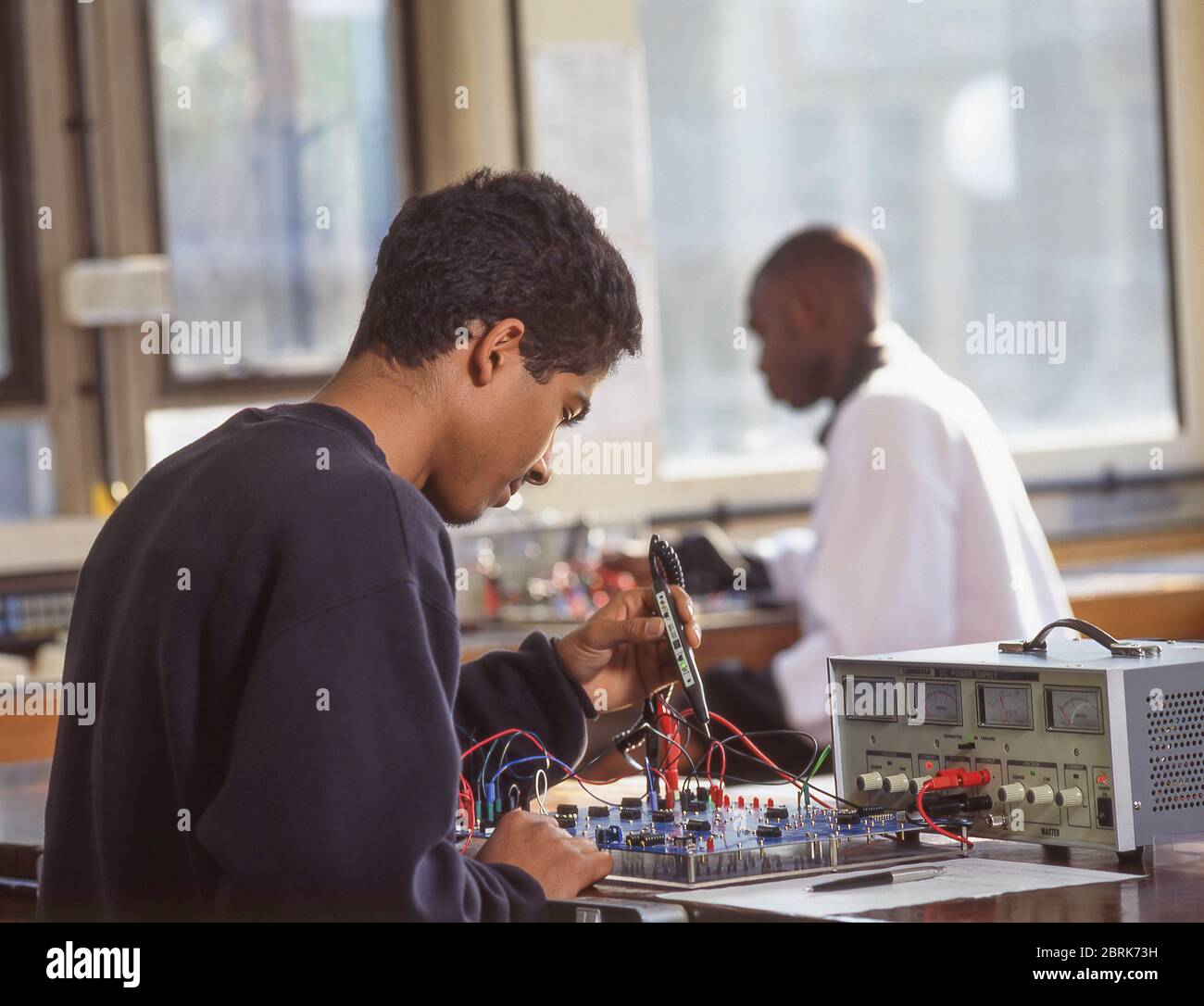 Studente di sesso maschile nero che lavora su attrezzature in classe elettronica, Surrey, Inghilterra, Regno Unito Foto Stock