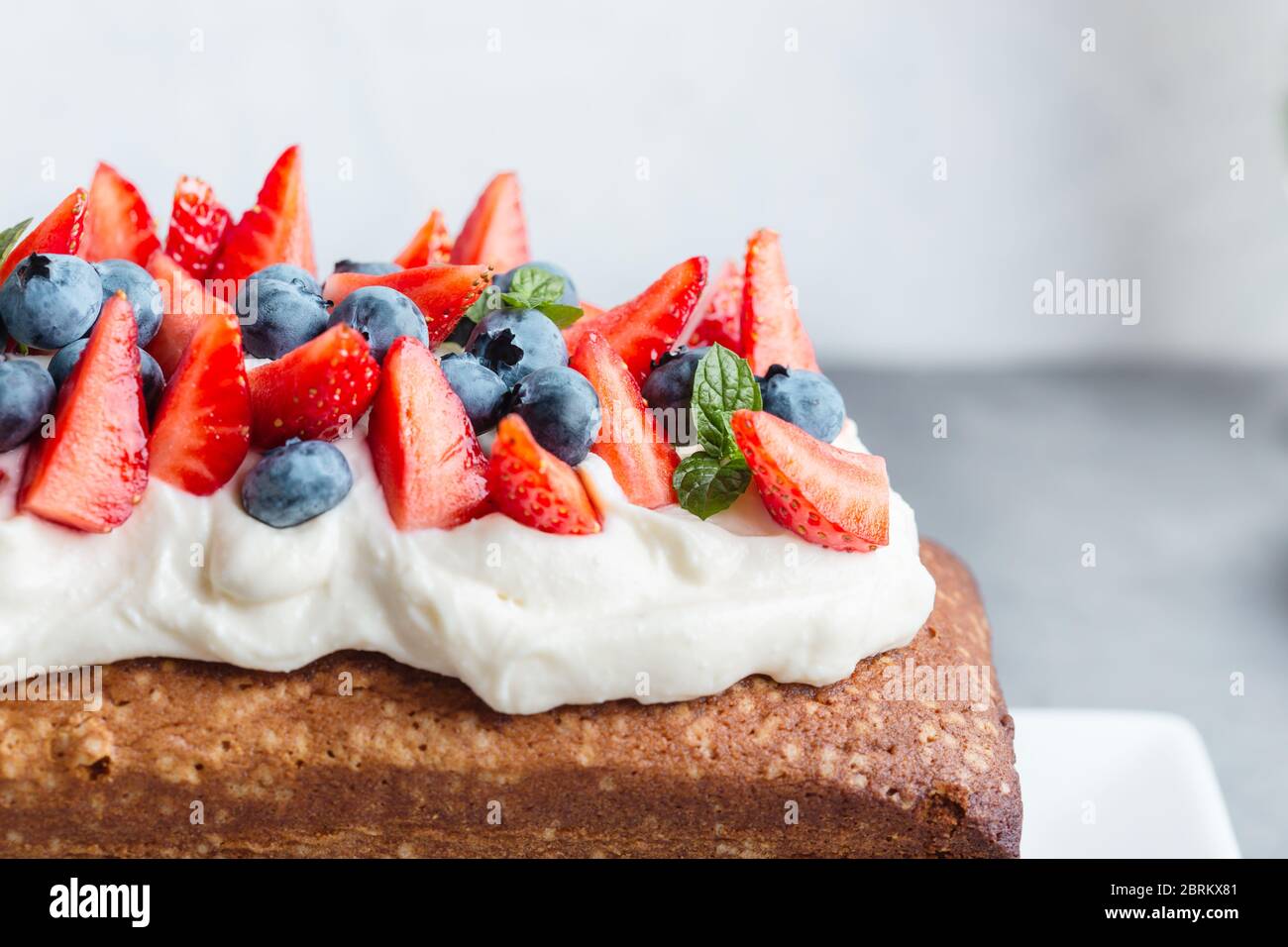 Dessert estivo, torta di frutti di bosco fatta in casa con glassa di formaggio cremoso, fragole fresche e mirtilli, primo piano Foto Stock