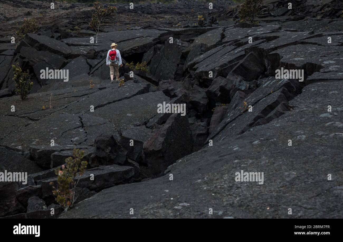 Una donna si trova sul cracked e caduto nella lava del pavimento del cratere Kilauea Iki, Hawaii Volcanoes National Park, Hawai'i, USA Foto Stock