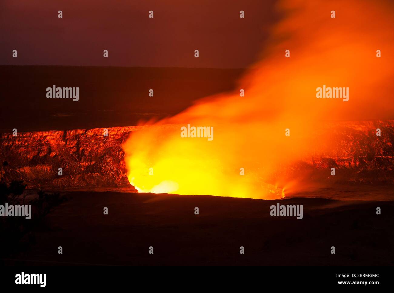 Kilauea Caldera è illuminata da gas che si sollevano e si inaridiscono e vapore dal lago di lava all'interno, visto dal centro visitatori, Hawaii Volcanoes Natia Foto Stock